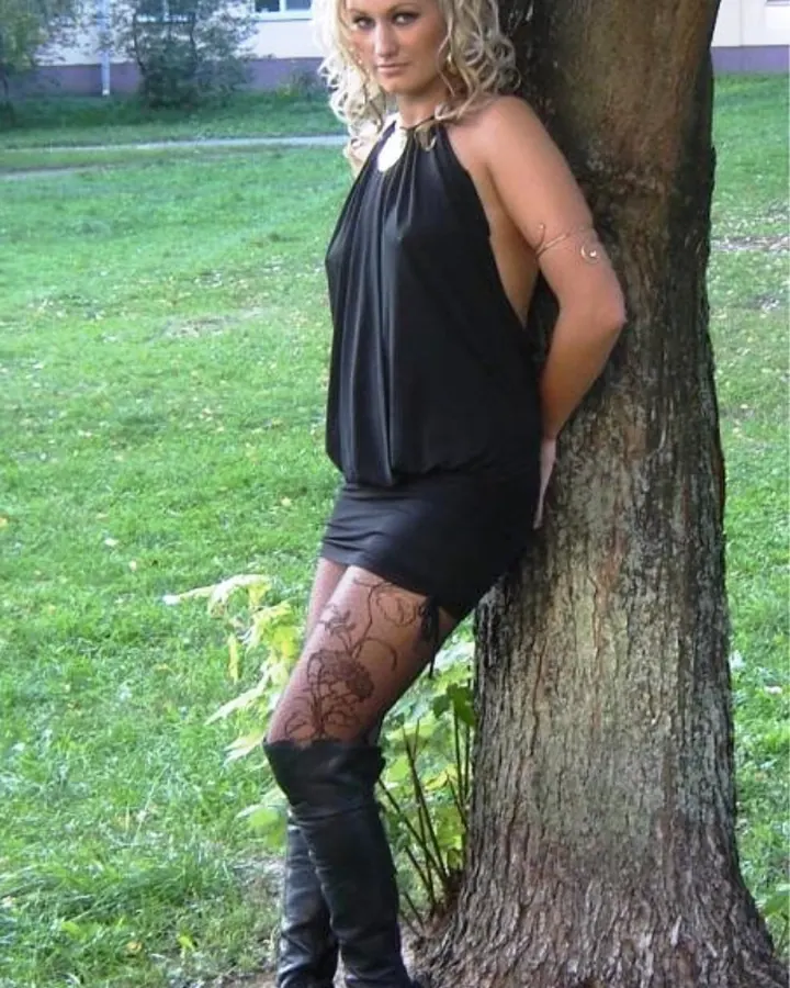 Femme blonde en haut noir, assise sur une chaise, regardant l'appareil