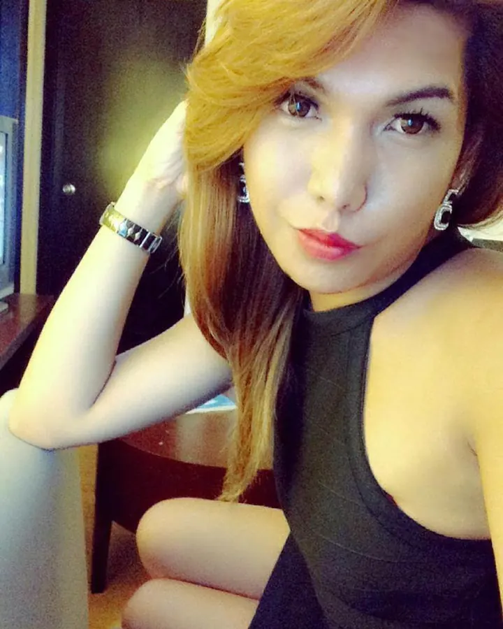 Femme aux cheveux orange, en robe noire, selfie dans une pièce
