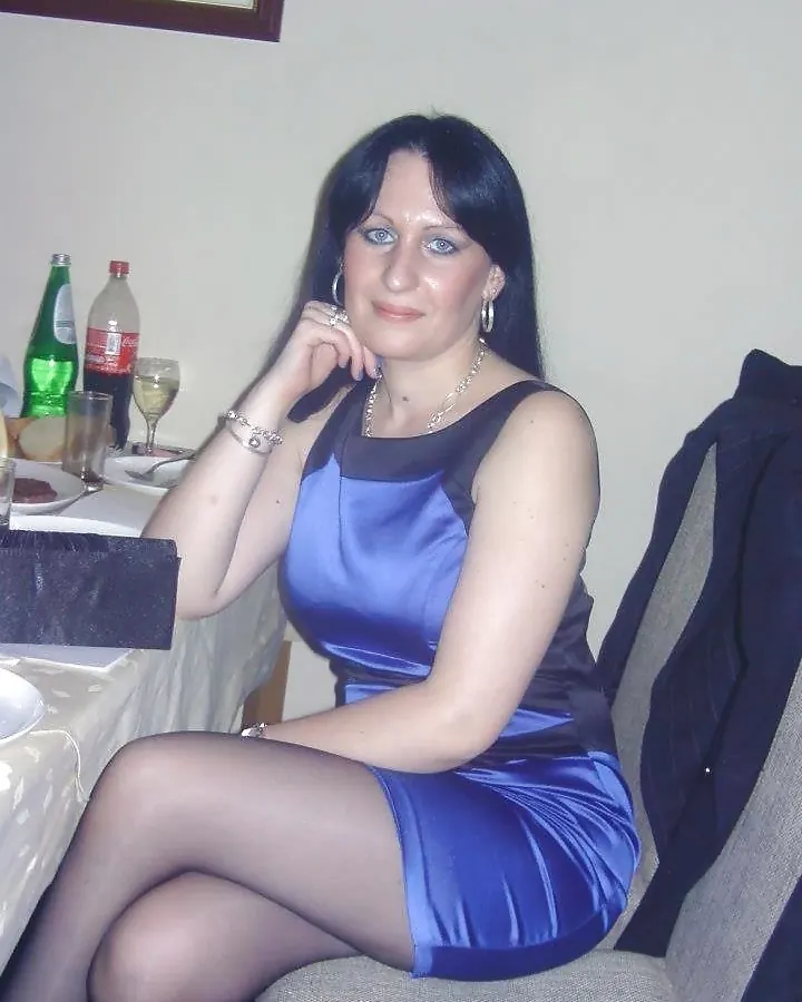 Femme aux cheveux bruns, en soutien-gorge noir, prenant un selfie dans une cuisine.