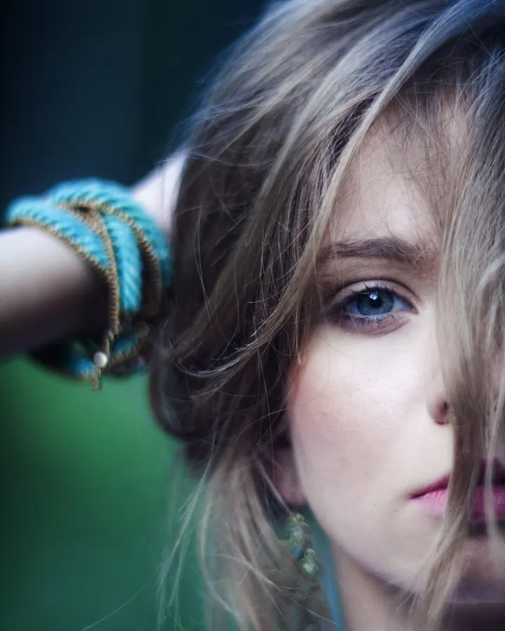 Portrait d'une jeune femme aux yeux bleus, cheveux blonds, regardant vers le bas.