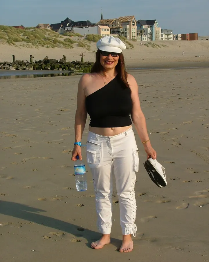 femme rousse en débardeur noir et pantalon blanc sur une plage