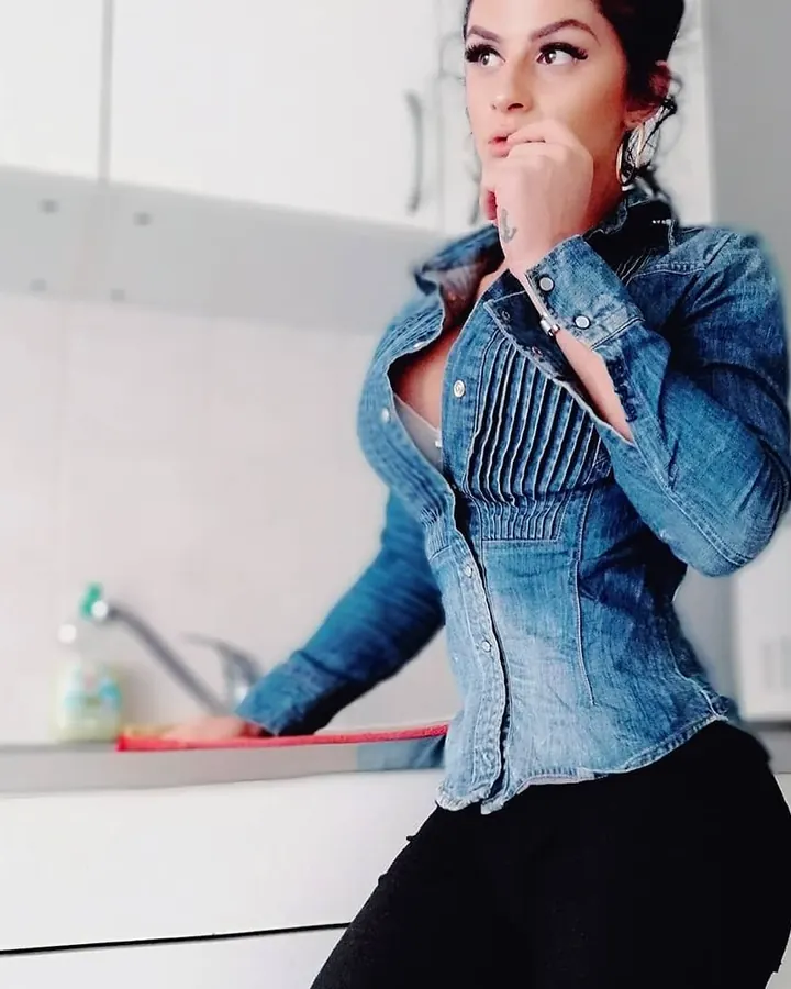 Femme en tenue de sport grise, prenant un selfie dans un miroir, mettant en valeur sa silhouette.